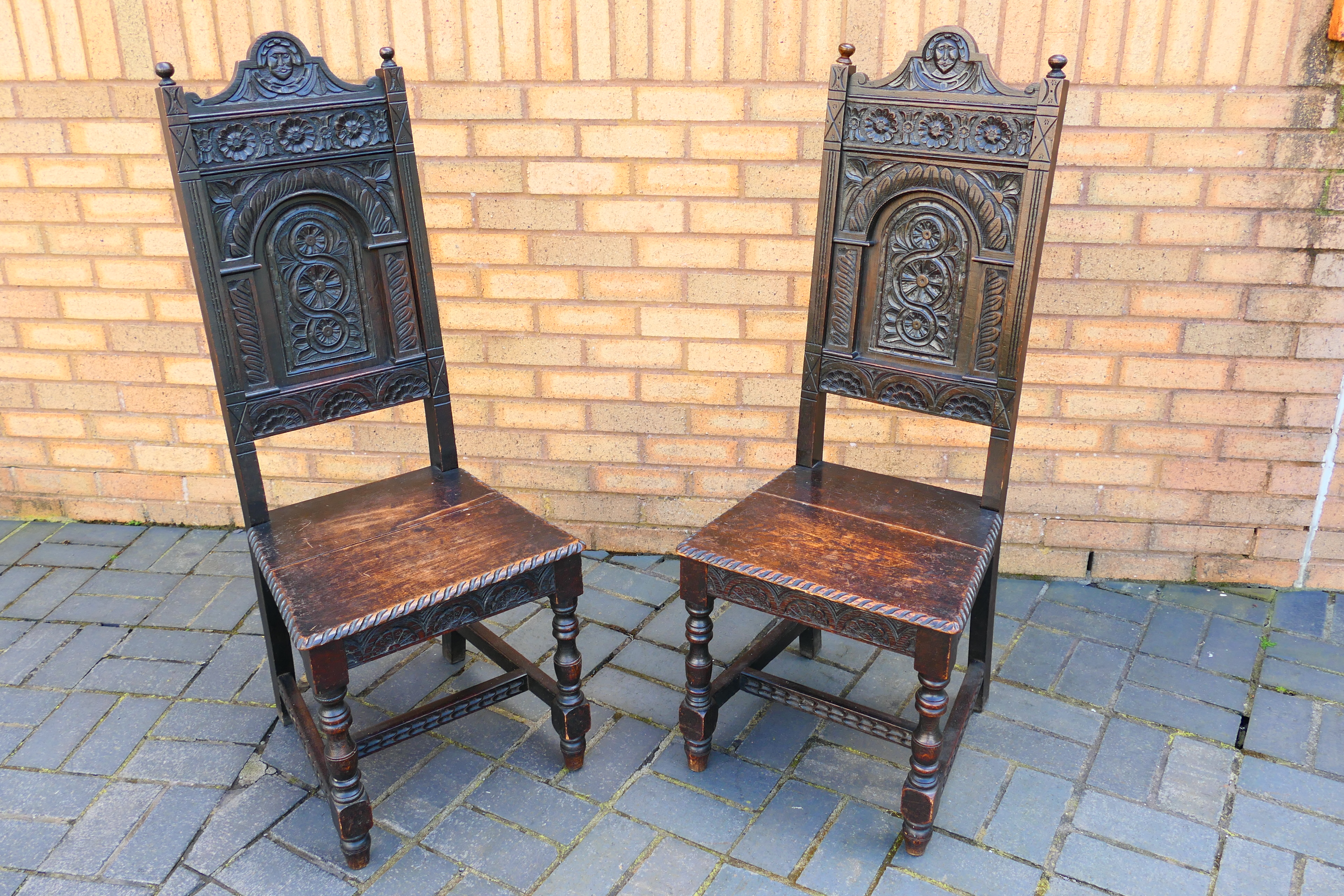 An antique pair of highly carved oak hall chairs. [2].