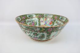 A large Cantonese famille rose punch bowl, typically decorated with panels of figures and flora,