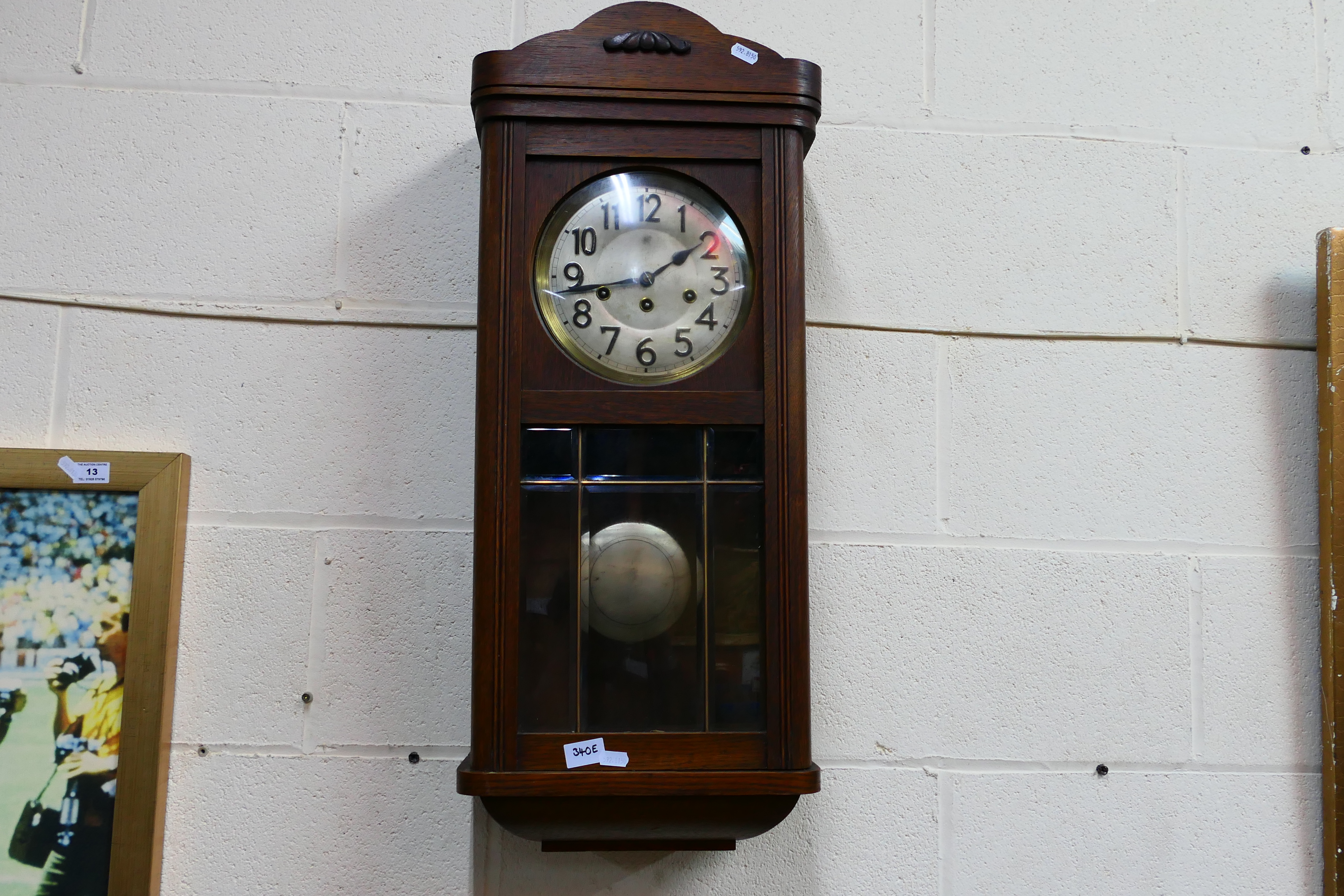 An oak cased wall clock, Arabic numerals to the dial, with pendulum.