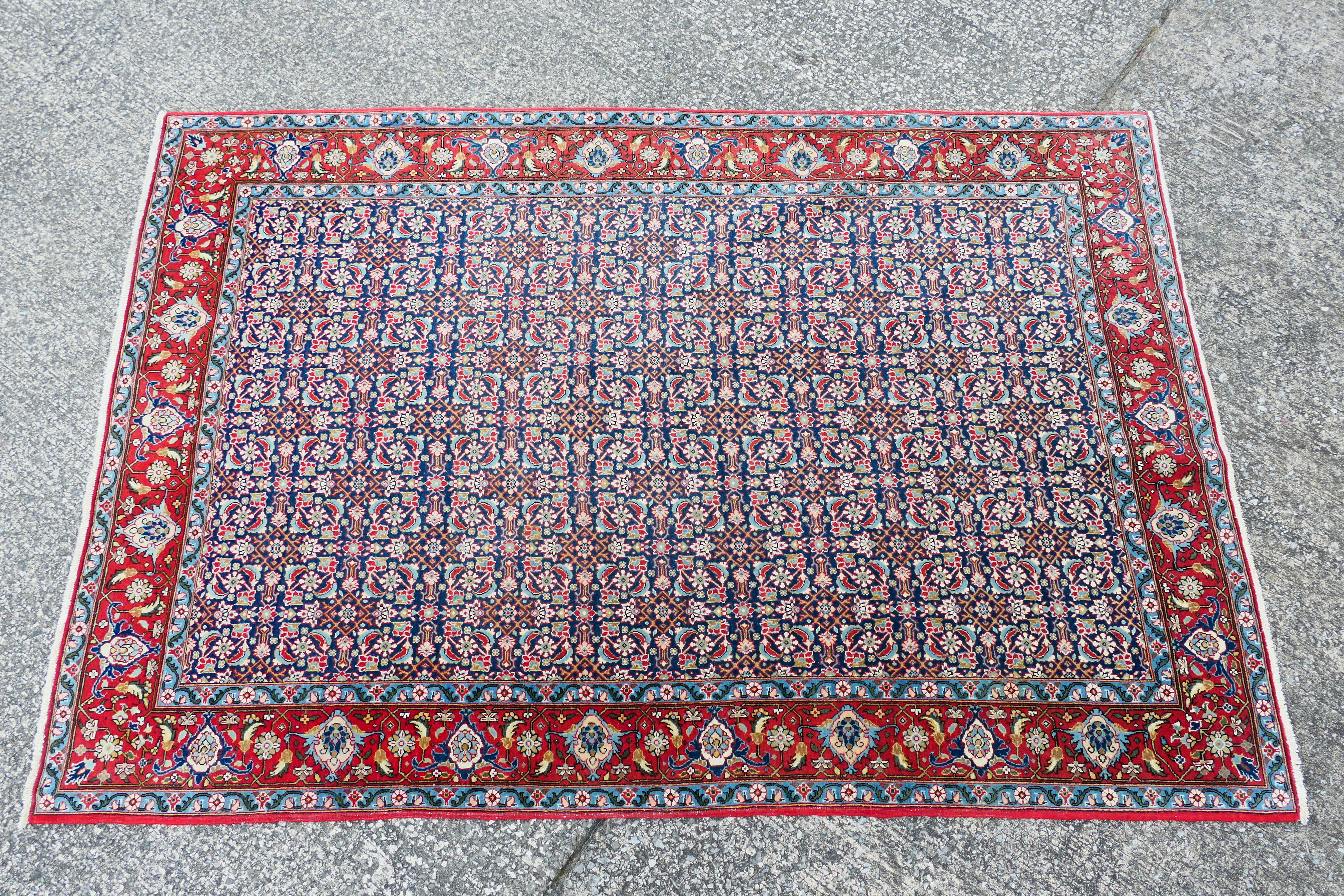 A Persian rug with central blue field with all over polychrome floral decoration within repeating