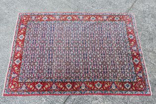 A Persian rug with central blue field with all over polychrome floral decoration within repeating