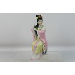 A Chinese figure depicting a seated lady combing her hair, approximately 23 cm (h).