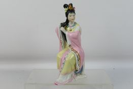 A Chinese figure depicting a seated lady combing her hair, approximately 23 cm (h).
