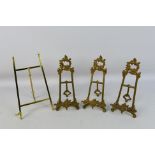 Three cast brass, easel plate stands and one similar.