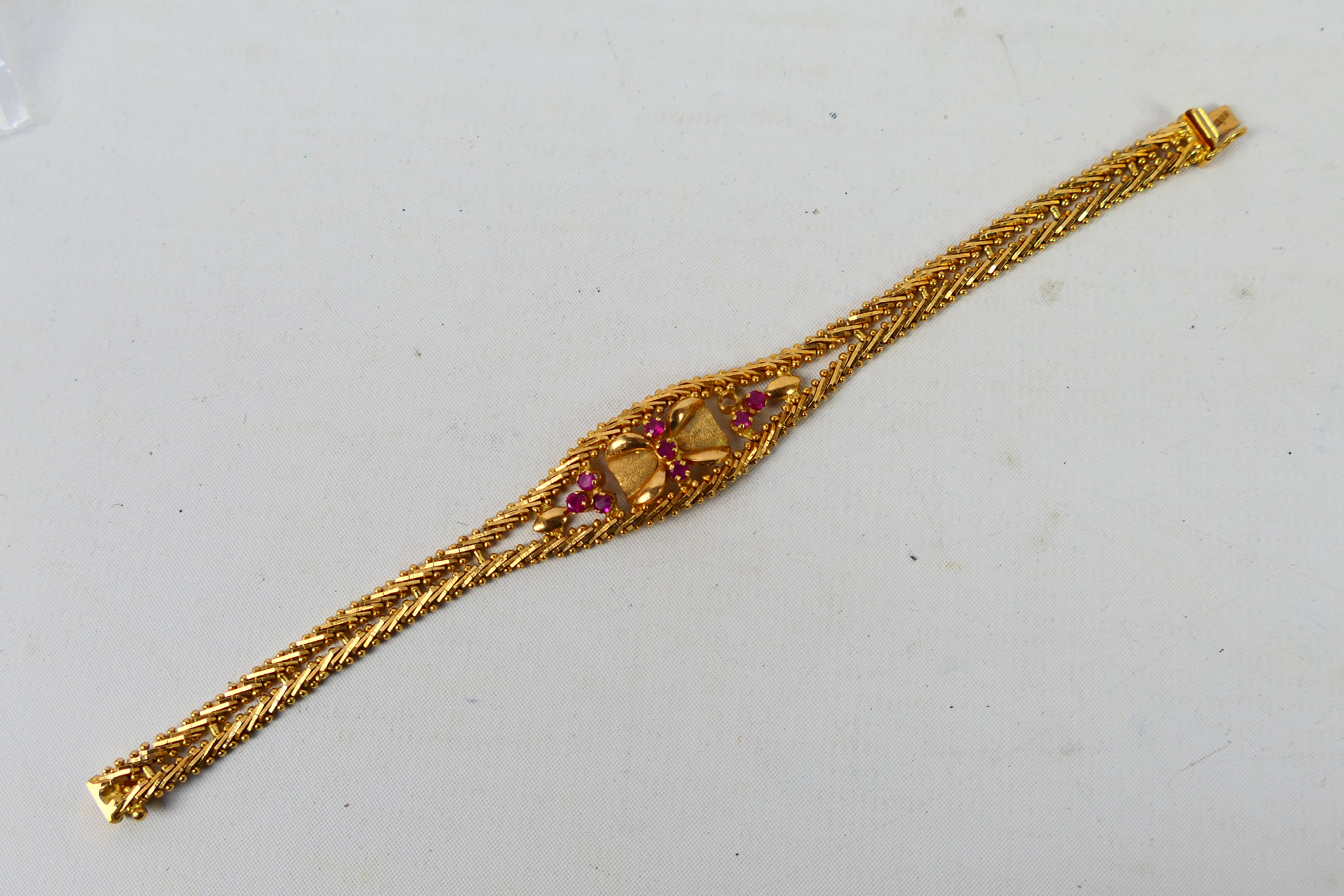 A yellow metal bracelet set with rubies (one stone lacking), stamped 750 and assessed as 18ct,