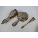 White metal mounted dressing table items comprising a hand mirror and brush with embossed