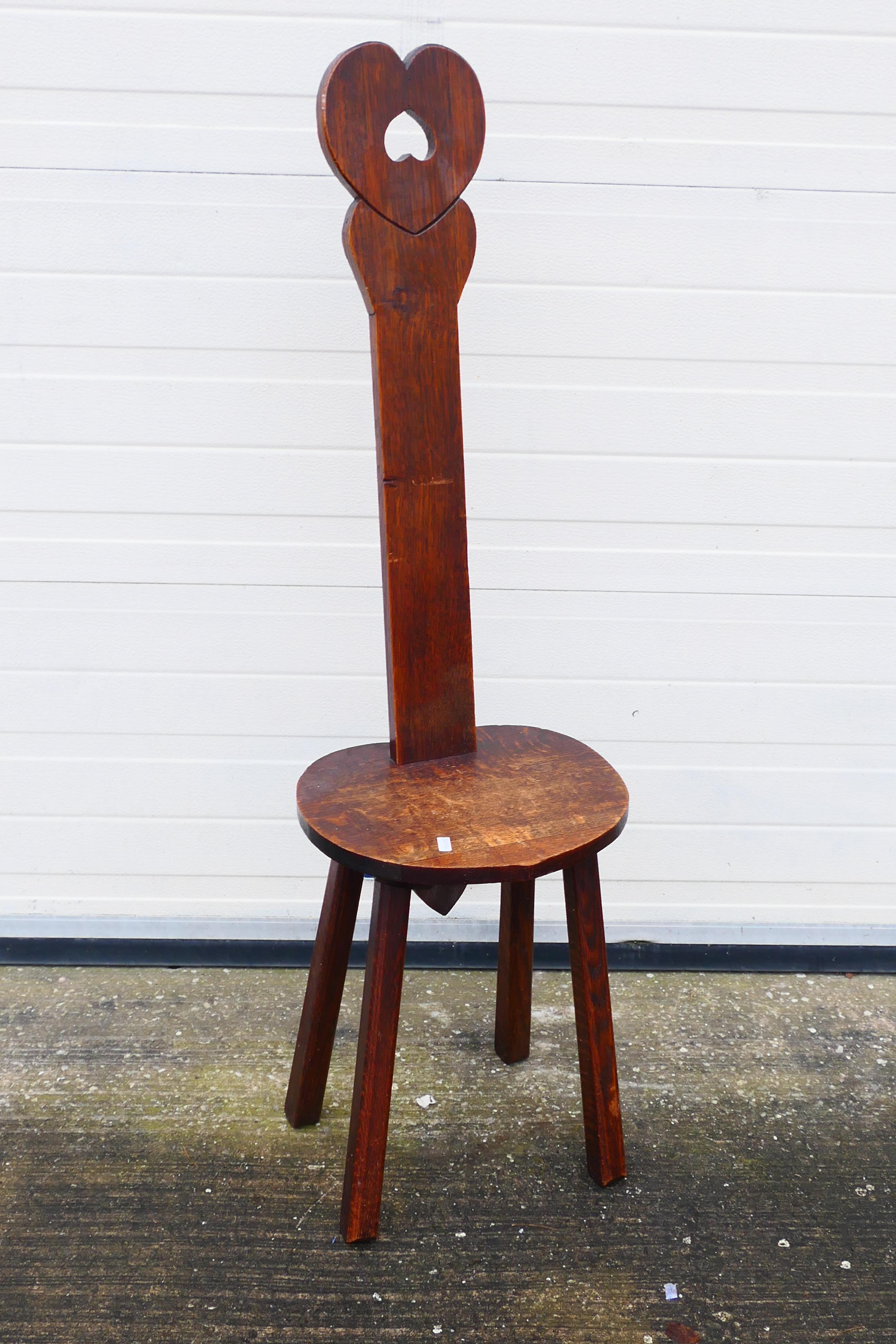 A wooden spinning chair with heart-shaped design. 120 cm (h) x 31 cm (d) x 35 1/2 cm (w).