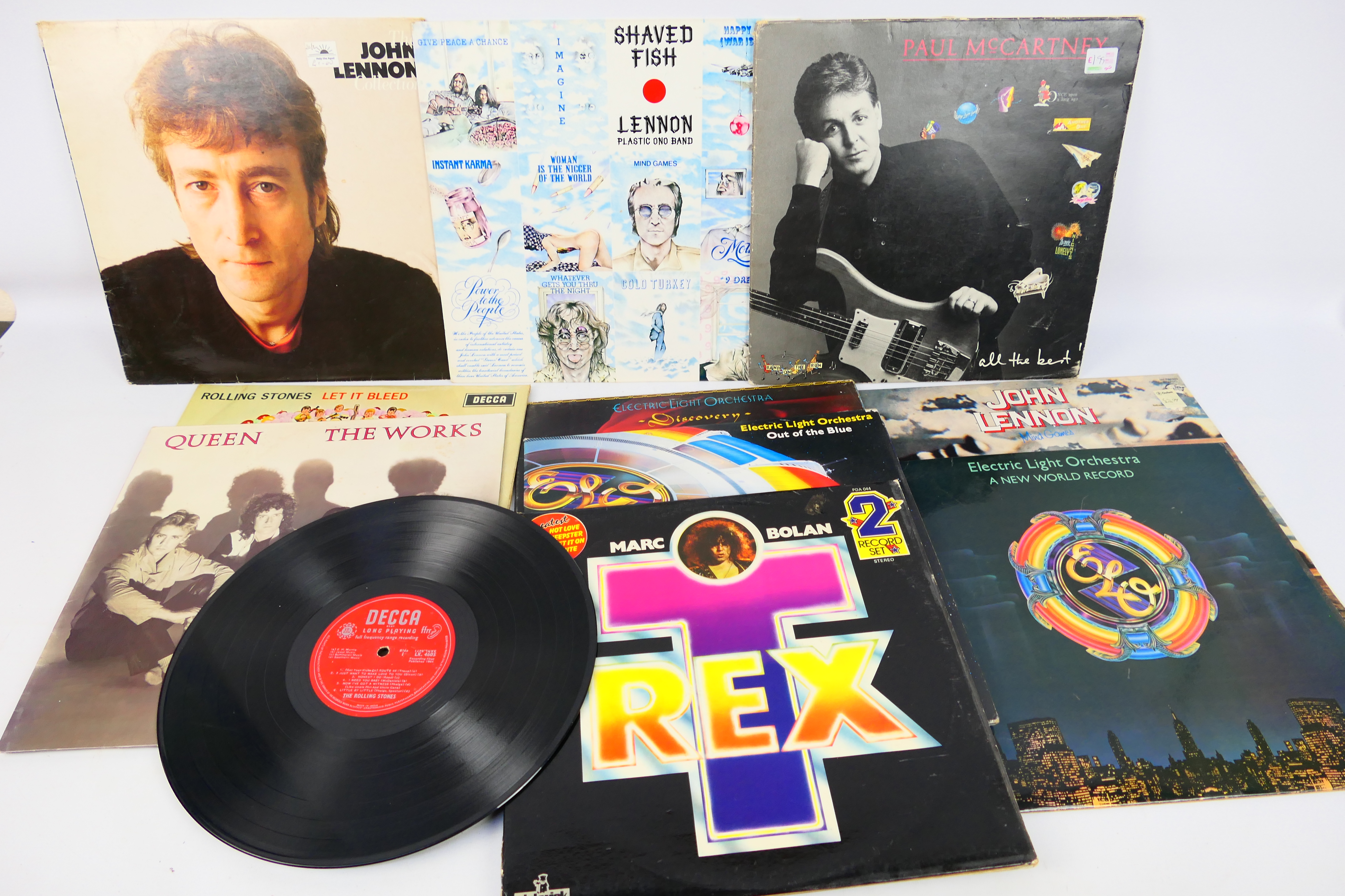 A collection of 12" vinyl records to include Rolling Stones, Queen, ELO, John Lennon,