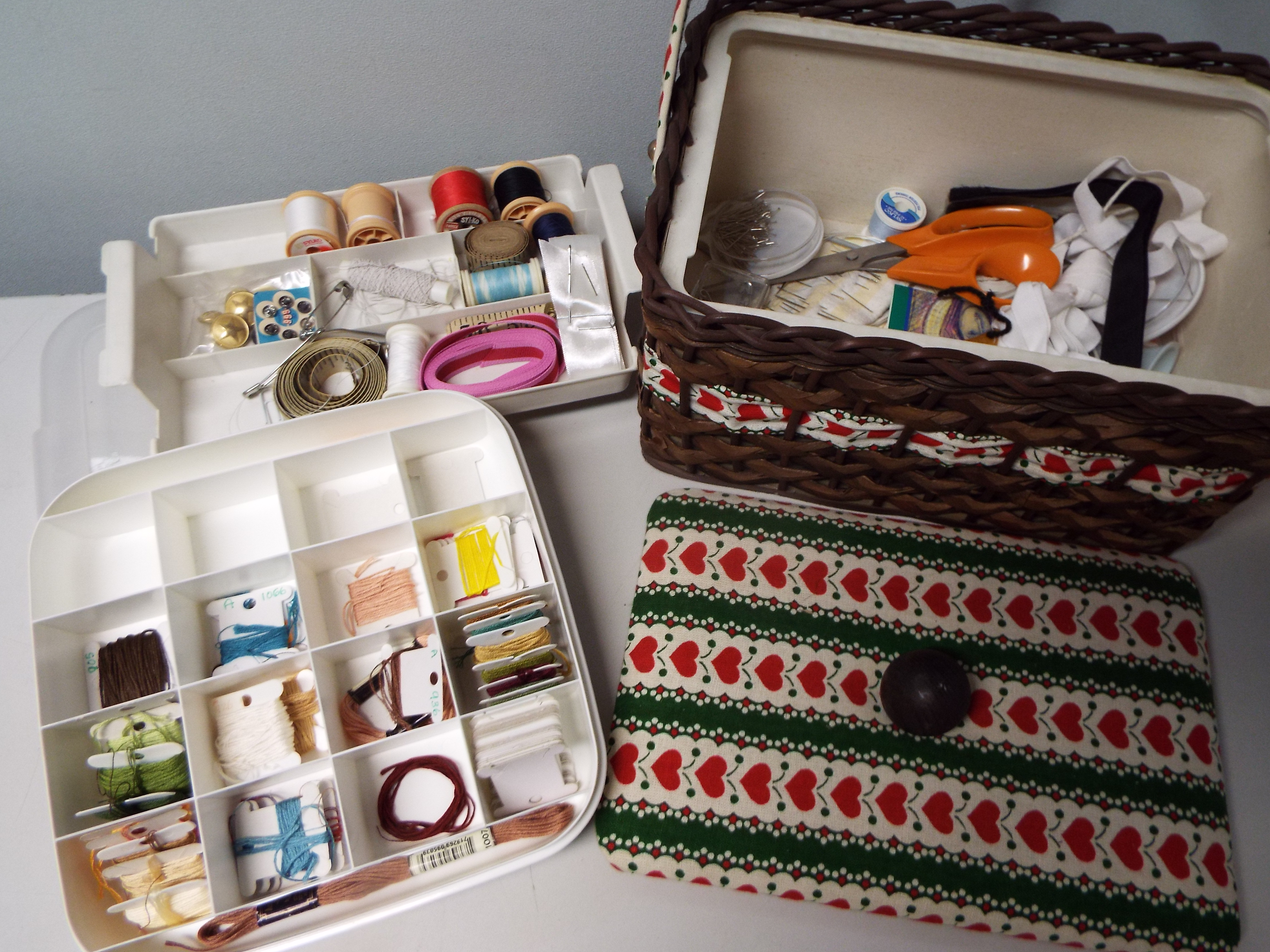 A needlework basket with swing handle and a further lidded plastic case,