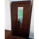 A wardrobe with carved decoration, single door with mirror to the exterior,