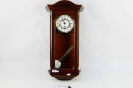 A London Clock Company wall clock with key and pendulum.