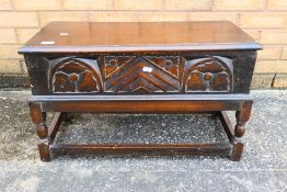 An antique sewing box stool with carved decoration to the front and all round stretcher,