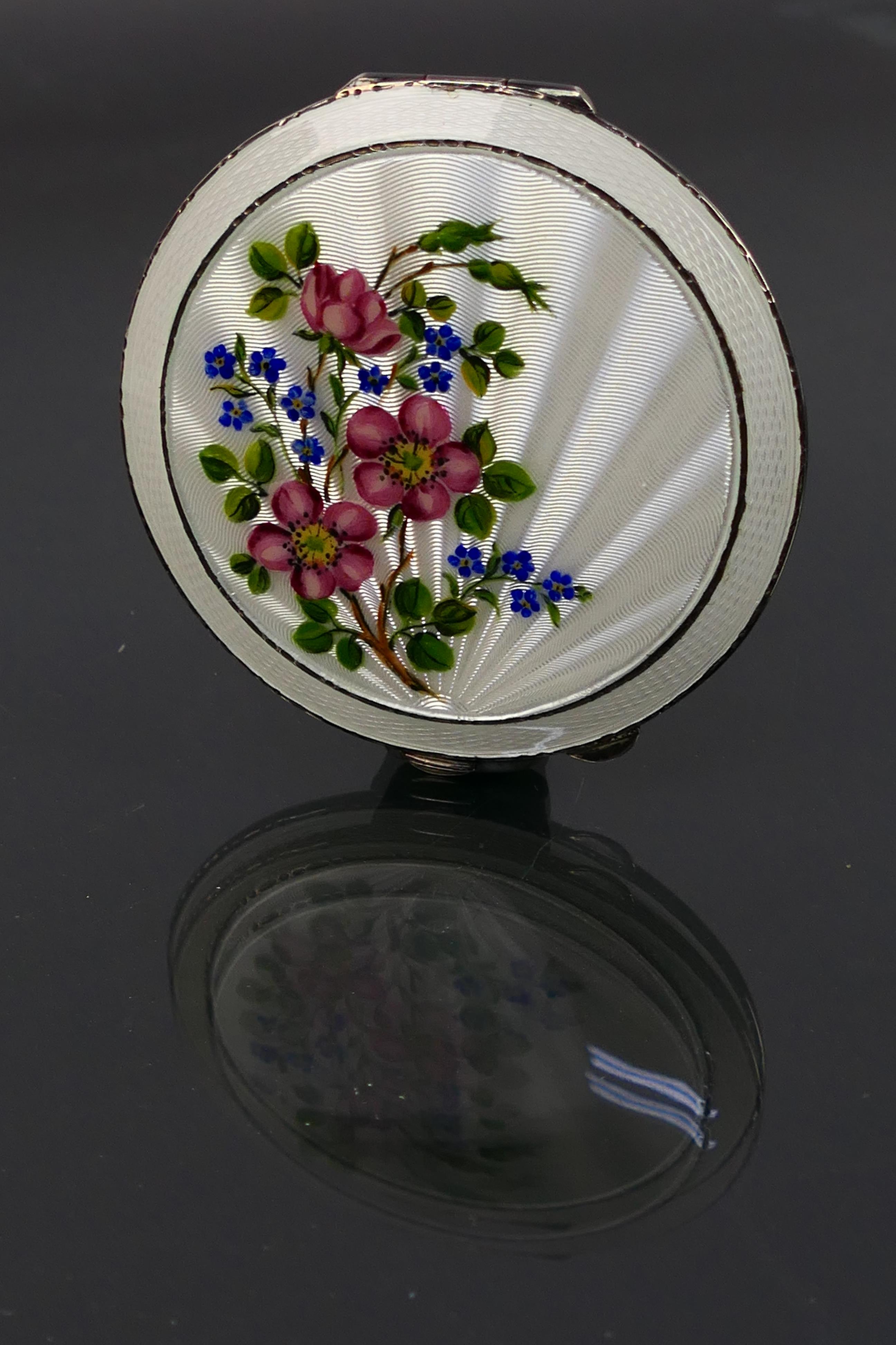 Henry Clifford Davis - A guilloche enameled powder compact with a floral display on the white