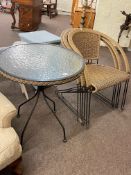 Circular glass topped wrought metal and wickerwork patio table and three chairs.