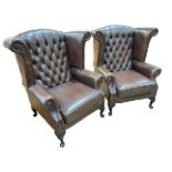 Pair Thomas Lloyd brown deep buttoned leather and studded wing armchairs.