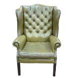 Olive green buttoned leather and studded wing armchair.