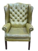 Olive green buttoned leather and studded wing armchair.