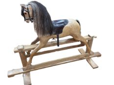 Polished wood rocking horse on safety stand, 106cm by 162cm.