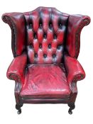 Ox blood buttoned leather and studded wing armchair.