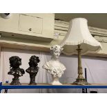Three ornate busts and a brass table lamp.