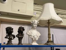 Three ornate busts and a brass table lamp.