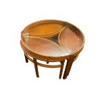 Circular glass topped teak coffee table with three oval nesting tables below.