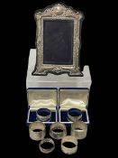 Seven silver napkin rings, and silver easel photograph frame.
