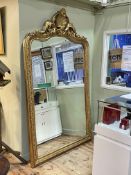 Large gilt framed arched top bevelled wall mirror with shell, swag and floral crest, 230cm by 140cm.