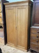 Pine wardrobe having two panelled doors enclosing base drawer, 201.5cm by 120.5cm by 57cm.
