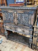 Carved oak side cabinet having two carved panel doors above two drawers on carved turned legs