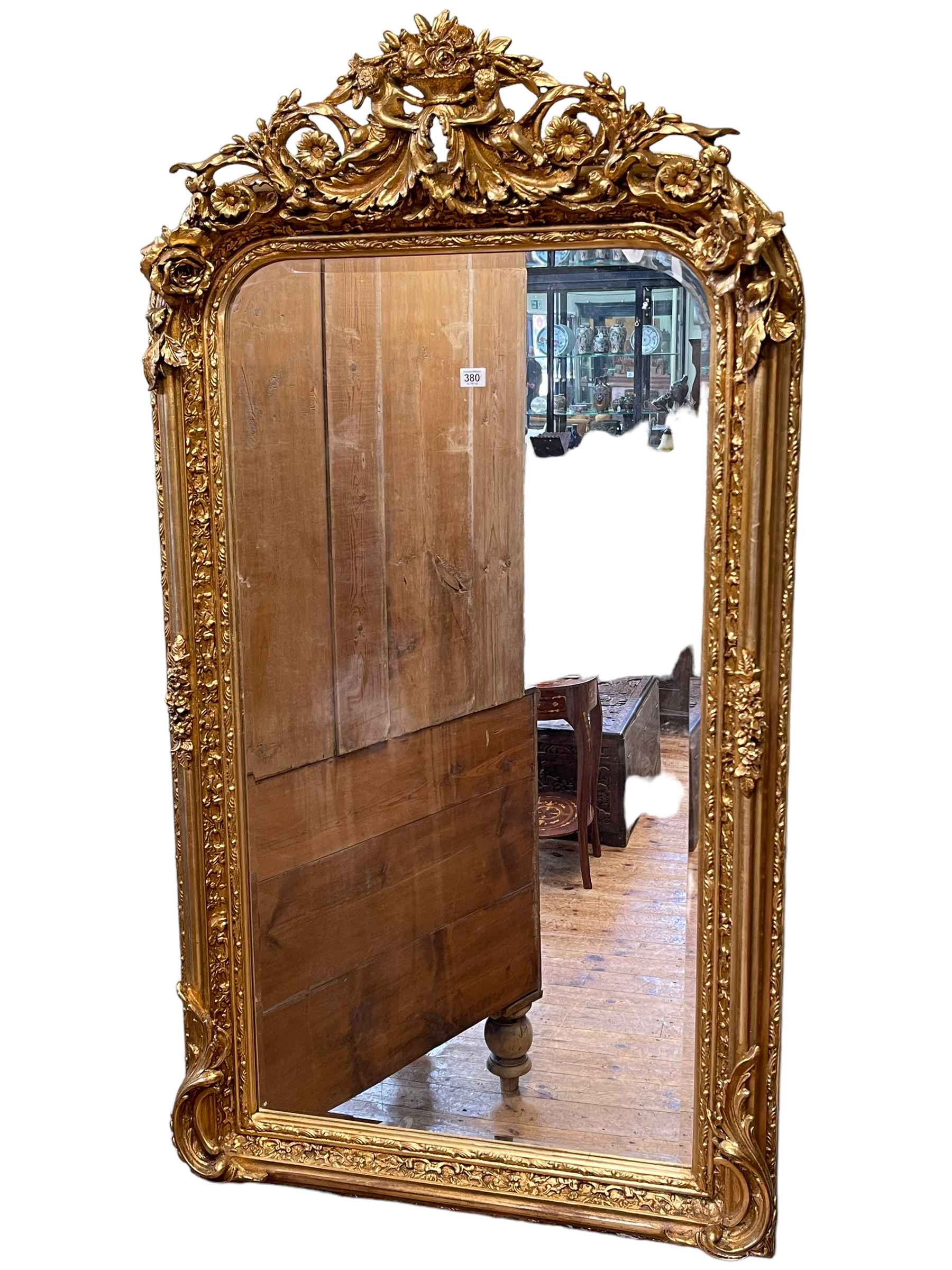 Gilt framed bevelled overmantel mirror with cherub and foliate crest, 152cm by 84cm.