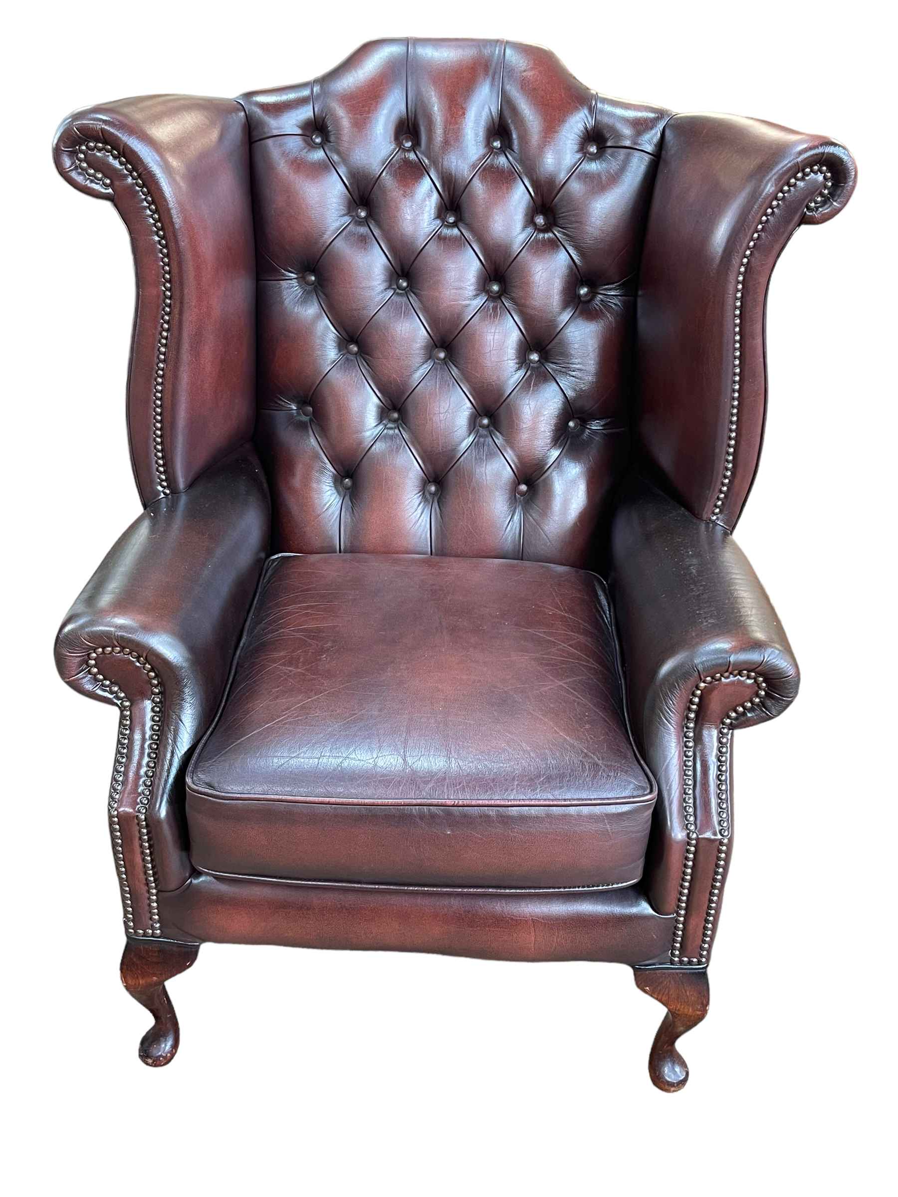 Brown deep buttoned and studded leather wing back armchair.