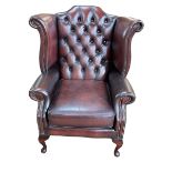 Brown deep buttoned and studded leather wing back armchair.