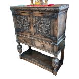 Carved oak side cabinet having two carved panel doors above two drawers on carved turned legs