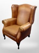 A contemporary tan leather wingback armchair,
