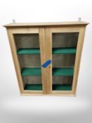 A glazed pine double door cabinet with shelved interior,