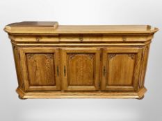 A carved oak sideboard, fitted cupboards and drawers beneath,