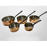 A graduated set of five cast iron-handled copper sauce pans,