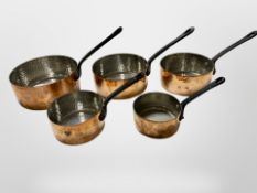 A graduated set of five cast iron-handled copper sauce pans,