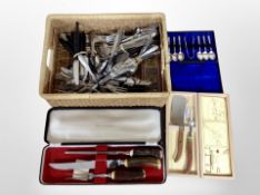 A wicker basket of assorted stainless steel table cutlery and cased three piece carving set with