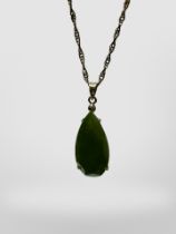 A cut pear-shaped green hardstone pendant on silver gilt chain