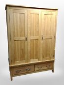 A contemporary solid oak triple door wardrobe,