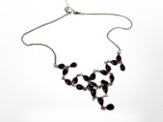 A silver necklace set with amethyst coloured cabochon stones.