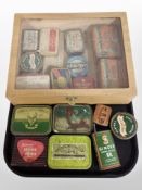 A glazed display case and a collection of vintage tins, cigarette tins,