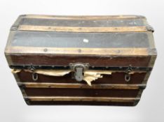 An early 20th century wooden bound dome top trunk containing linen.