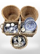 Five wicker baskets containing assorted blue and white willow pattern and other ceramics