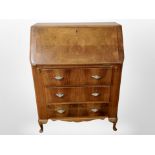 A 1930's walnut veneered three fall front bureau,