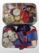 A vintage tin containing vesta case, assorted badges and ribbons, American 5¢ coins, etc.