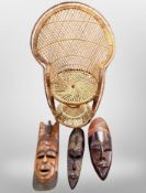 Three African carved hardwood masks and a wicker child's chair