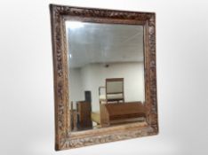 A Scandinavian heavily carved oak bevelled mirror,
